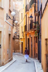 Mujer caminando en callejón con casas de Valencia, España