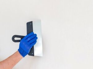 Mano pasando herramienta para alisar pared